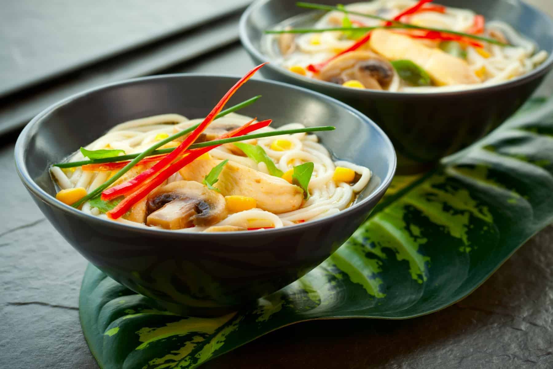 Bowls of Asian noodle soup with chicken,mushrooms, sweetcorn and chilli